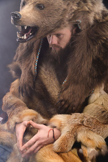 A bearded shaman is sitting dressed in skins, looking thoughtfully aside. magic in business
