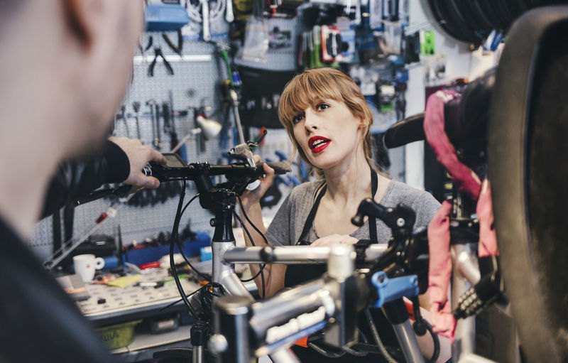 Female mechanic talking to customer in bicycle repair shop