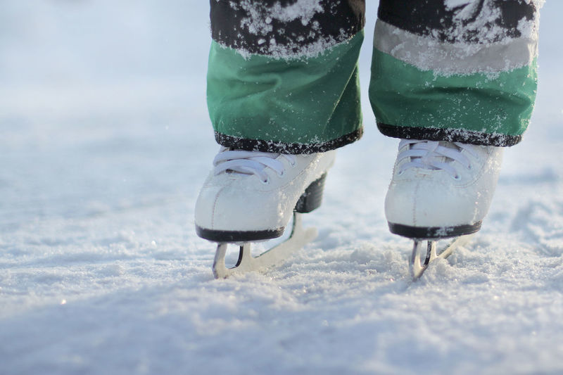 Children feet in white skates stand on the ice. ice skating on a frosty winter day.