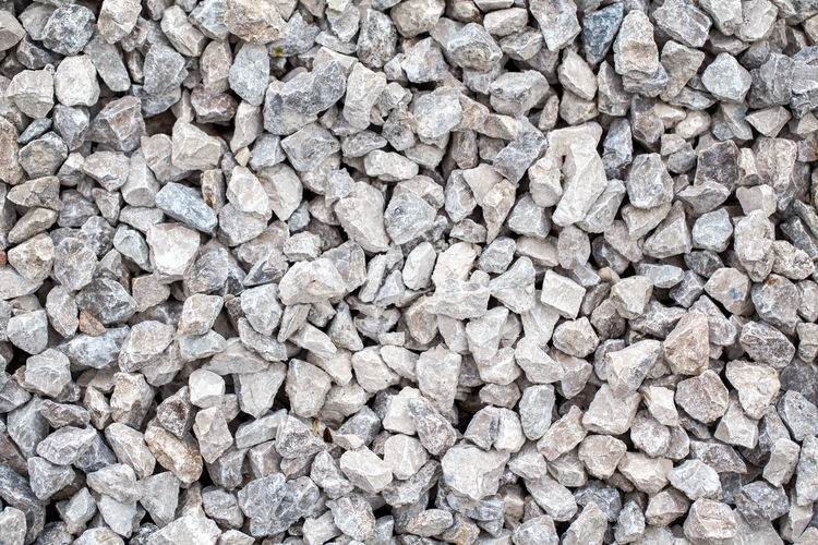 Closeup of small crushed stones rocks lying on ground. natural environmental background texture. 