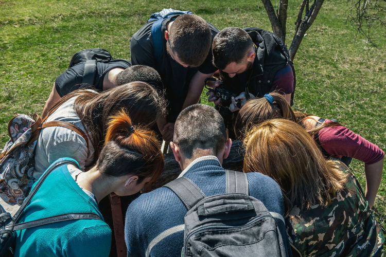 High angle view of friends with backpacks huddling while standing at park