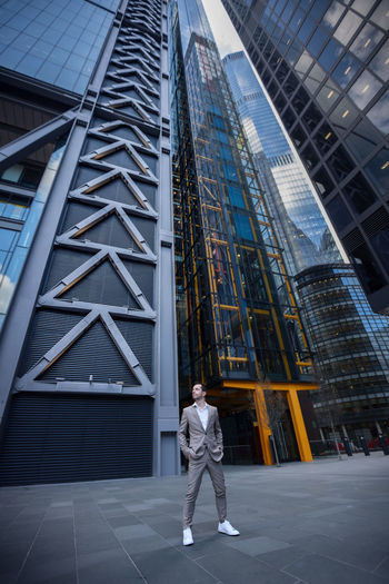 Full length of man standing against modern buildings in city