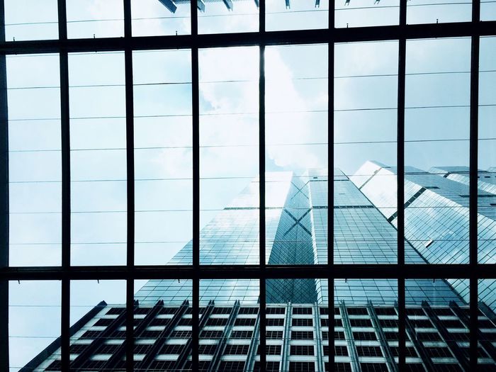 Modern buildings against sky seen through glass window