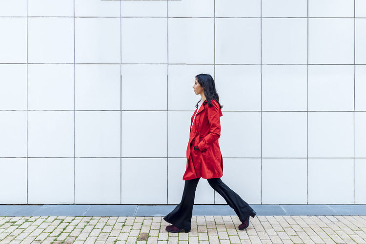 Businesswoman walking on footpath by wall