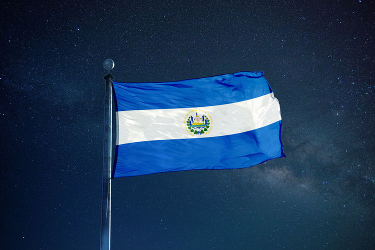 Low angle view of el salvadoran flag against star field sky