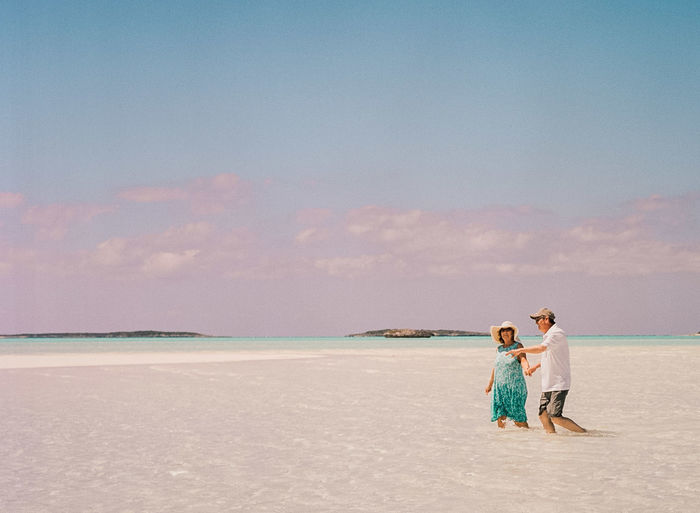 Couple walking in sea against sky