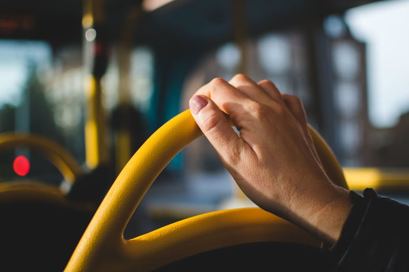 Cropped hand of woman on vehicle seat in bus