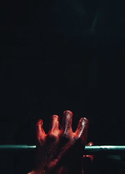 Cropped image of blooded hand on railing in darkroom