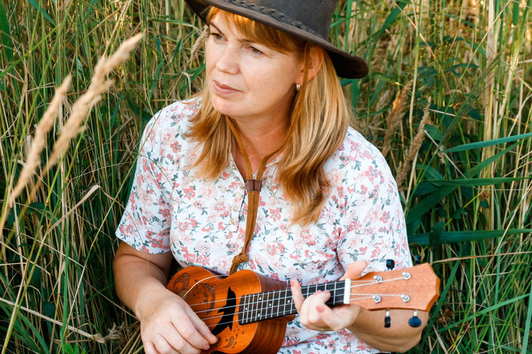 Woman with guitar on nature background. women outside on green meadow. ukulele chord. summertime. 