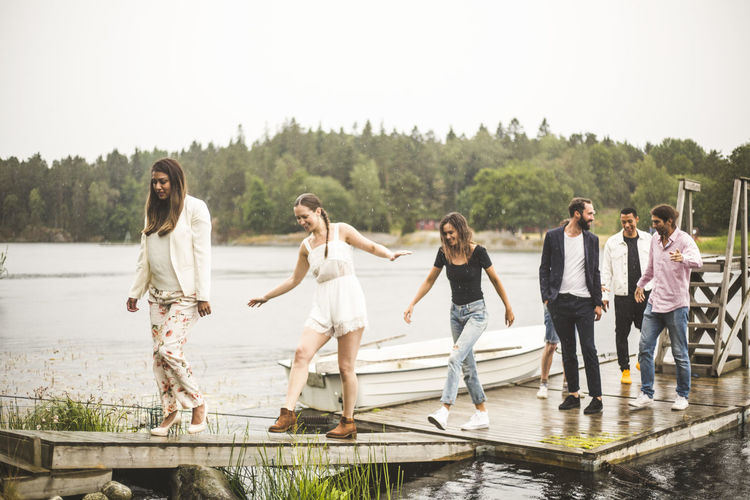 Multi-ethnic friends on jetty over lake during weekend getaway