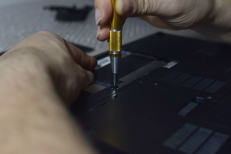 Cropped image of man repairing laptop at workshop