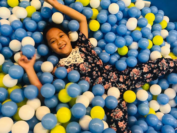 High angle view portrait of smiling girl lying in ball pool