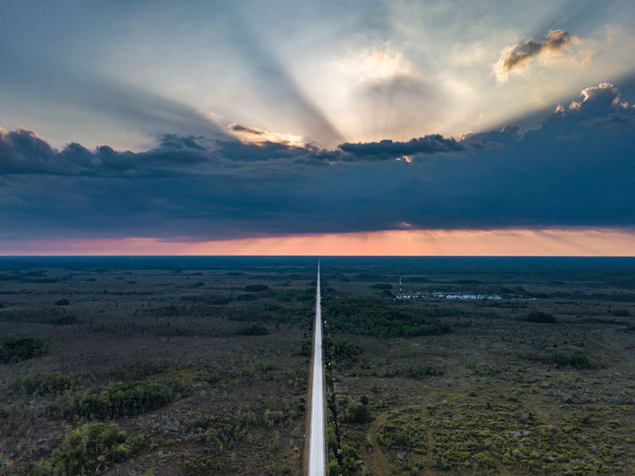 Scenic view of road amidst field during sunset
