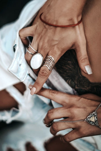 Female hands with silver boho rings and jewelry button up the stylish jeans