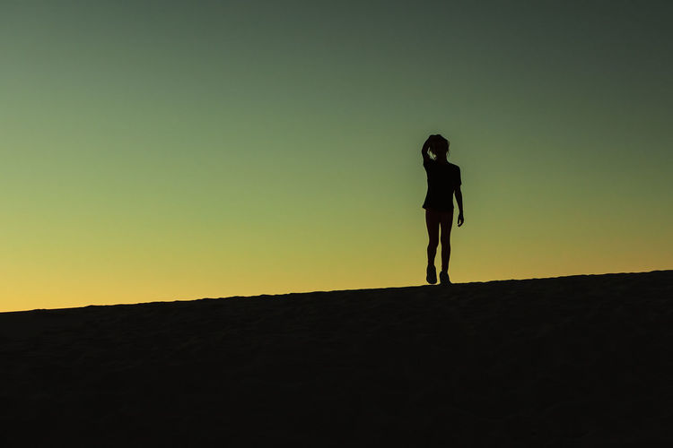 Silhouette man standing against clear sky during sunset