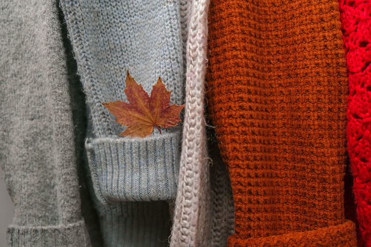 Stack of cozy knitted warm sweater with autumn fall maple leaf. sweaters in retro style. orange 