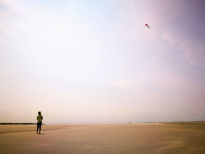 Man flying over beach against sky