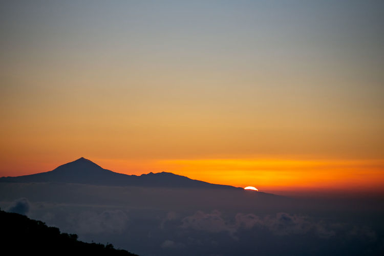 Scenic view of silhouette mountains against romantic sky at sunset