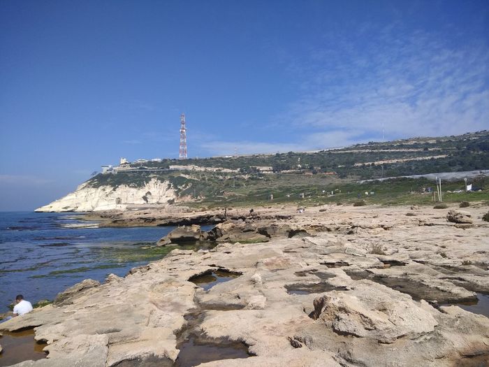 Rocks on beach against blue sky