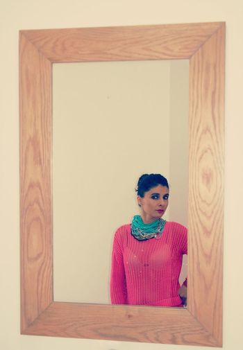 Portrait of woman standing against wall at home