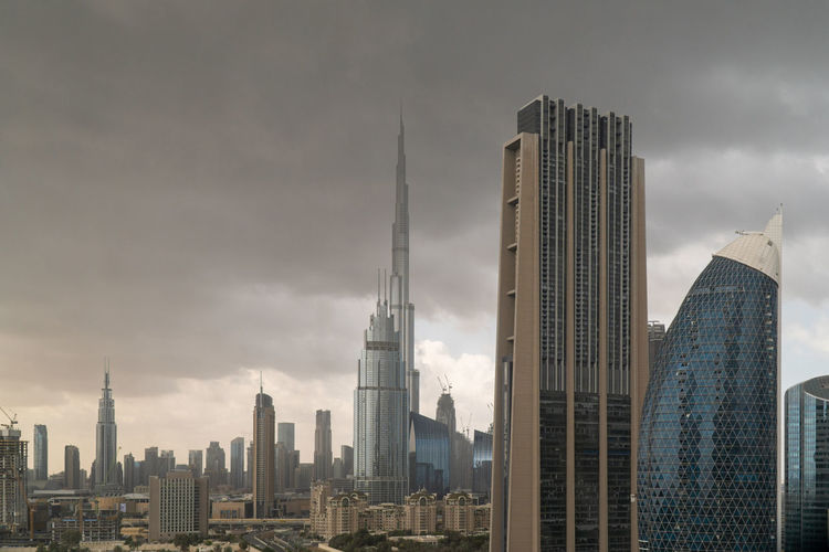 Buildings in city against stormy sky
