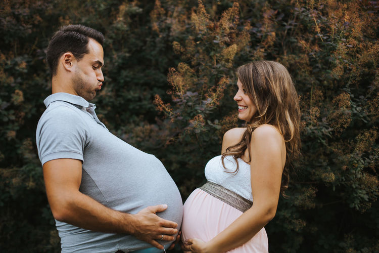 Man imitating pregnant wife outdoors