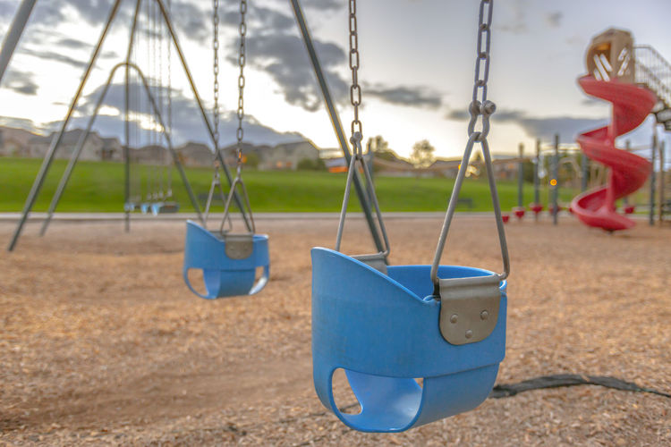Empty swings at playground during sunset