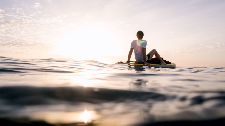 Concept: tranquility and relaxation. man sitting on paddle surf