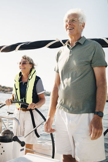 Woman sailing boat standing by senior man on sunny day