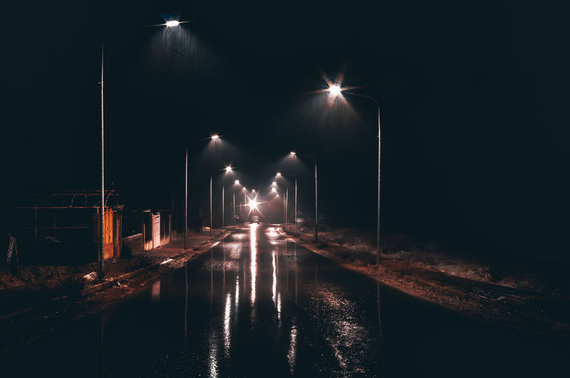 Illuminated street lights by road at night