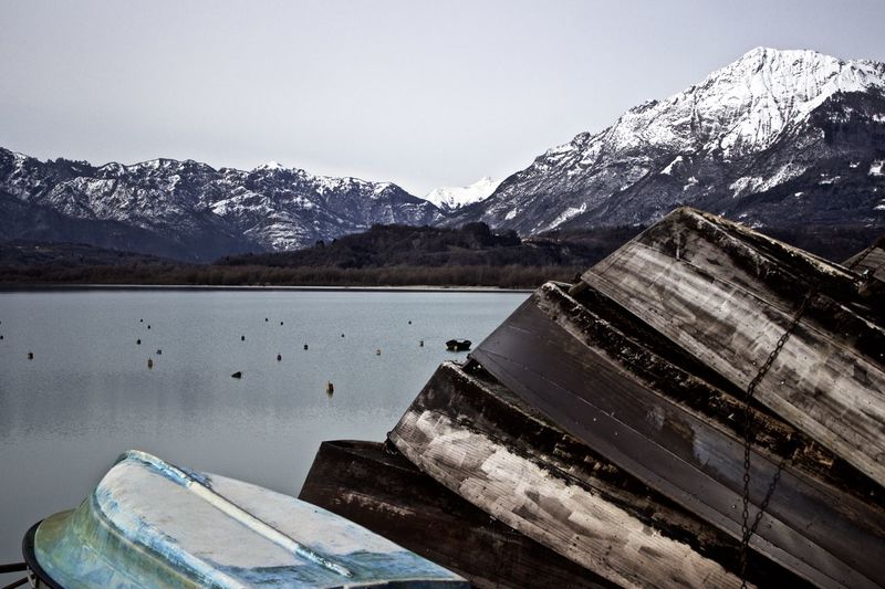 Upside down boats moored on lake by mountains