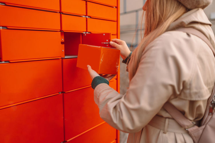 Rear view of woman standing against orange wall