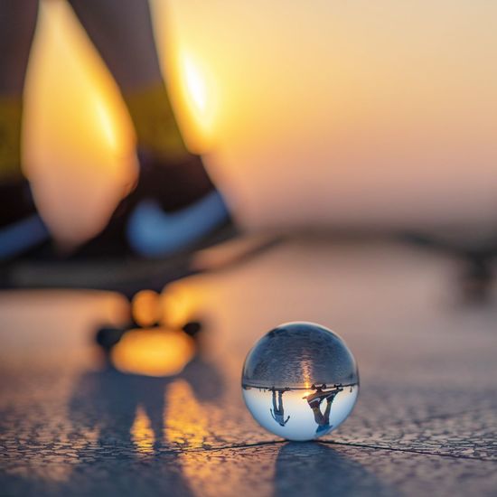 Close-up of illuminated ball on tiled floor against sky during sunset