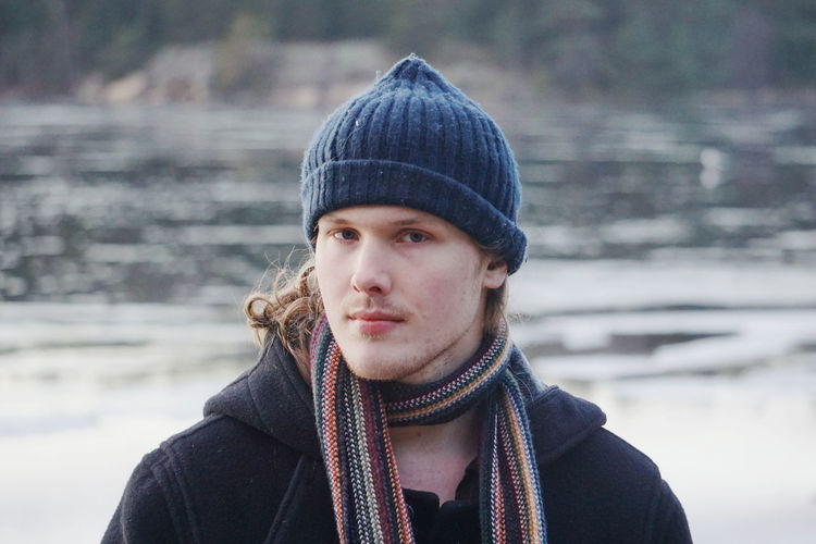Portrait of young man against lake during winter