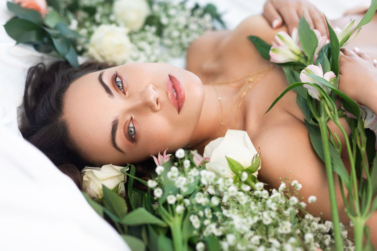 Portrait of shirtless woman lying on flowers