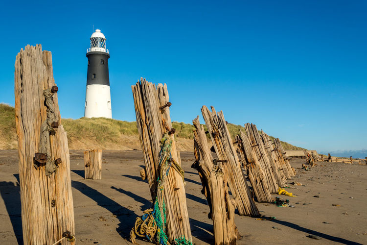 Wood at beach against blue sky