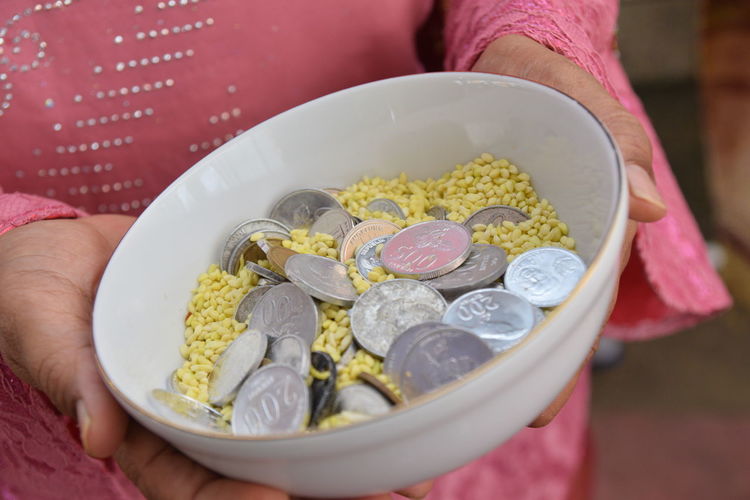 Midsection of woman holding food with coins in container