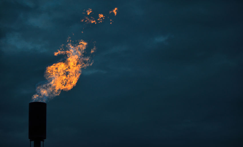 A methane flare burns against a twilight sky