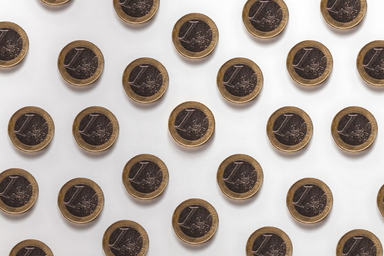 Directly above shot of coins arranged on white background