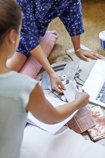 Cropped image of interior designers choosing curtain samples while sitting in workshop
