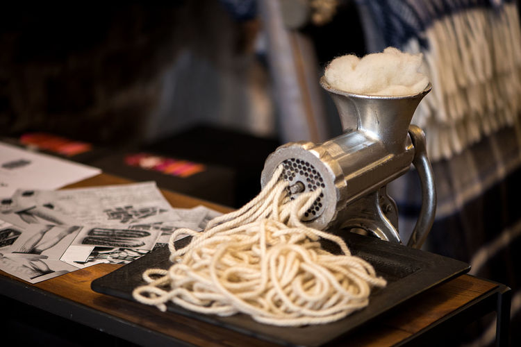 Close-up of pasta coming out from maker on table