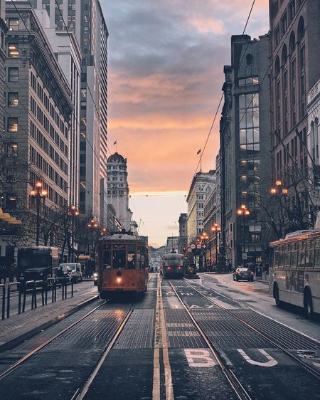 Tramway on street against cloudy sky during sunset