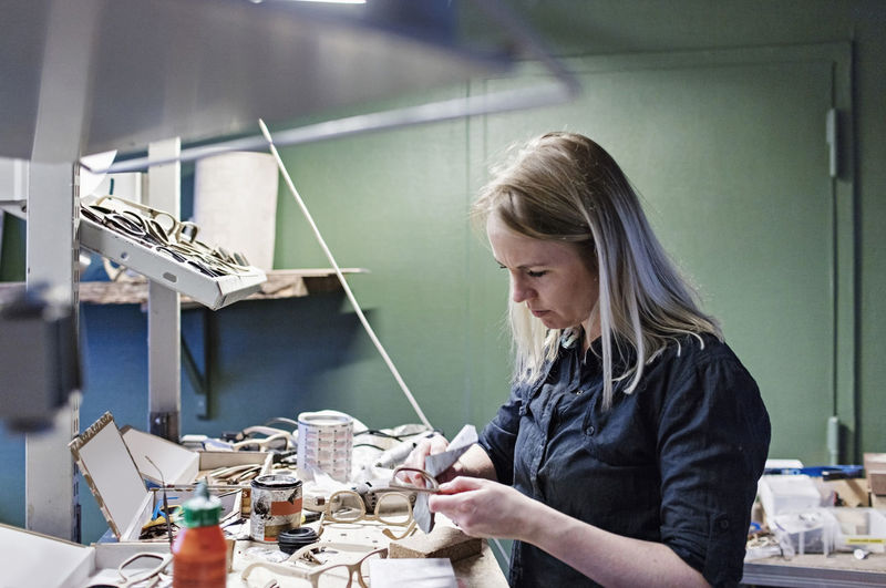 Female owner making eyeglasses in workshop