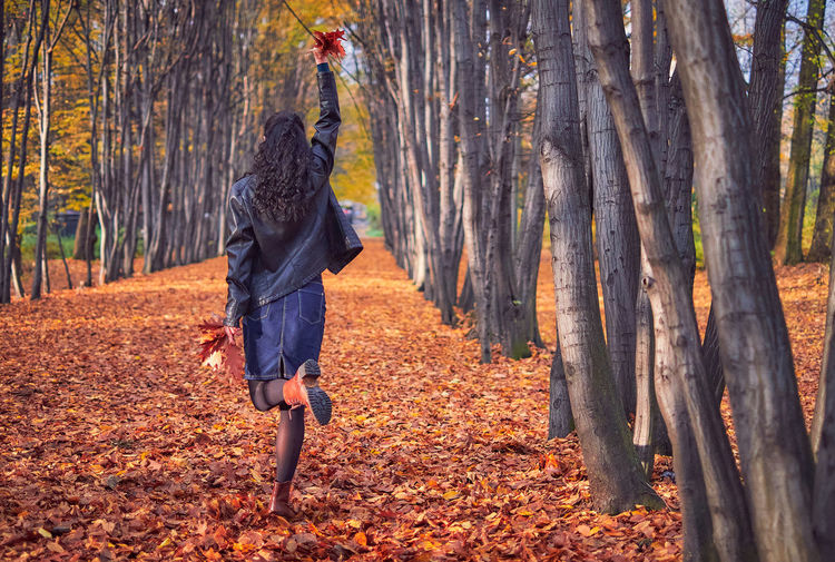 Full length rear view of woman walking amidst trees in forest