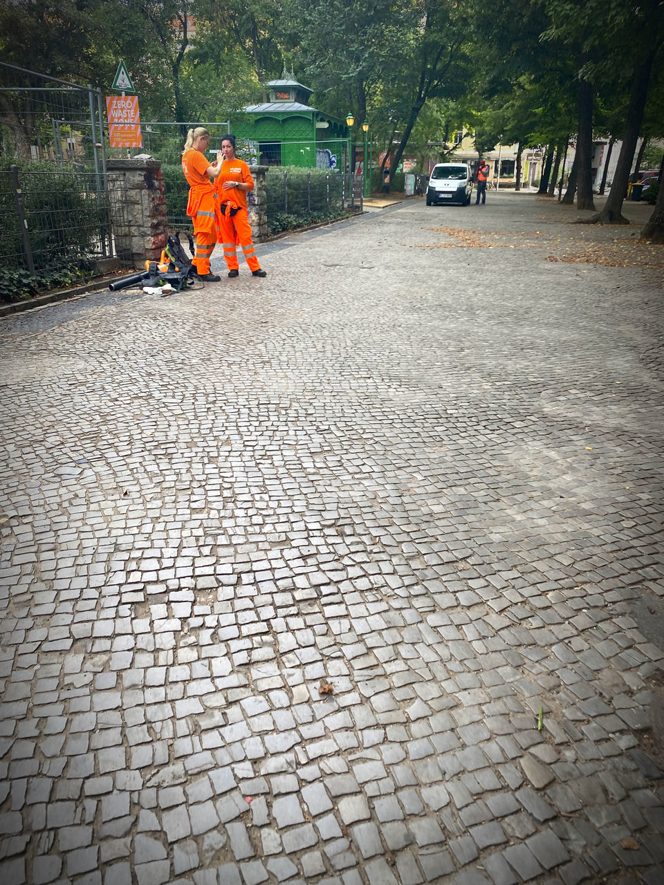 road surface, asphalt, street, city, transportation, cobblestone, men, road, architecture, occupation, day, footpath, mode of transportation, full length, tree, working, paving stone, sidewalk, outdoors, clothing, plant, two people, protection, nature, walking, adult, land vehicle, flooring, walkway