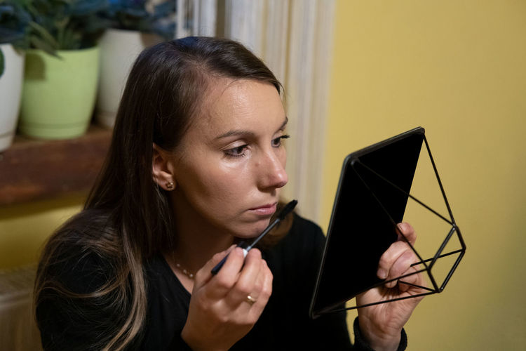 Woman applying mascara while looking at mirror