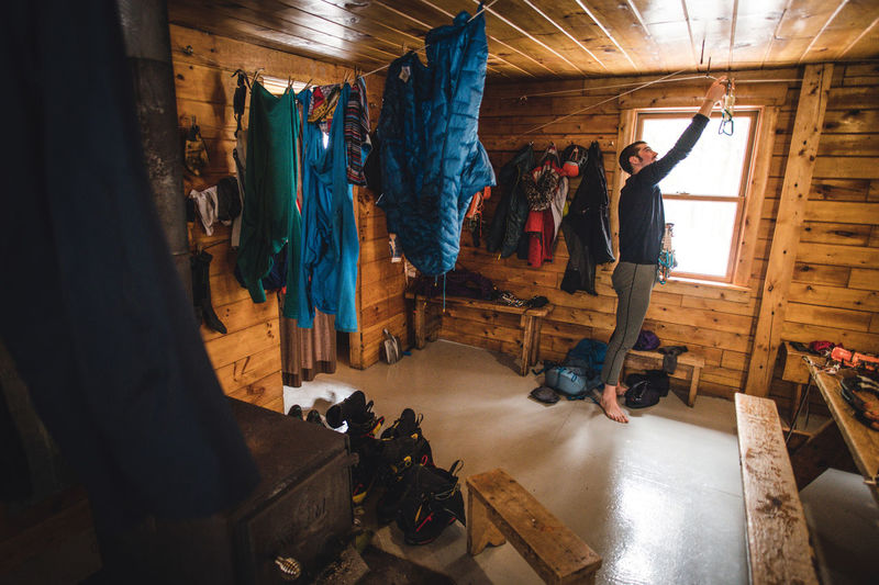A man sorting and drying climbing gear in a cabin during the day
