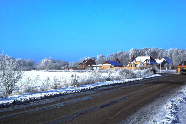 Snow covered road against clear blue sky
