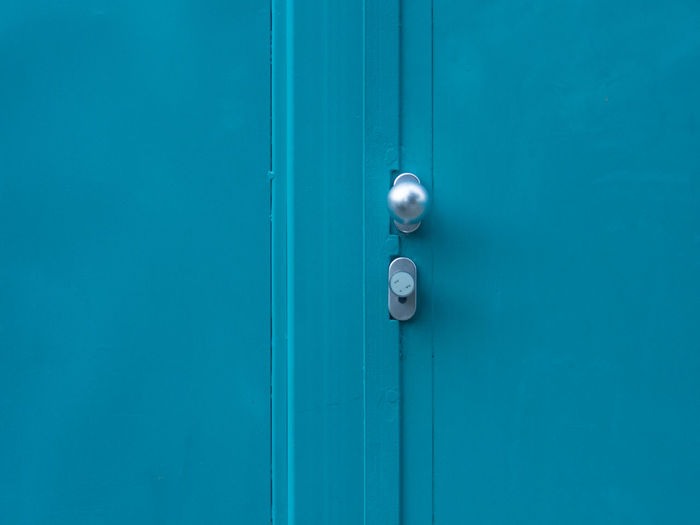 Silver doorknob on closed blue metallic door