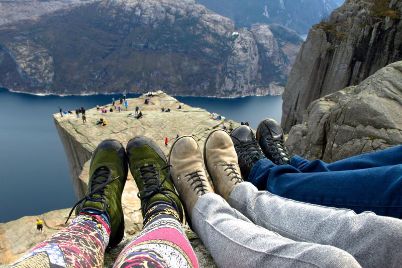 Low section of friends sitting on cliff against river